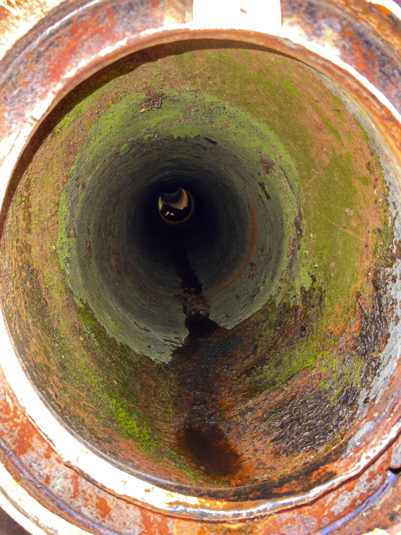 Interior of an old metal pipe with rust and green buildup
